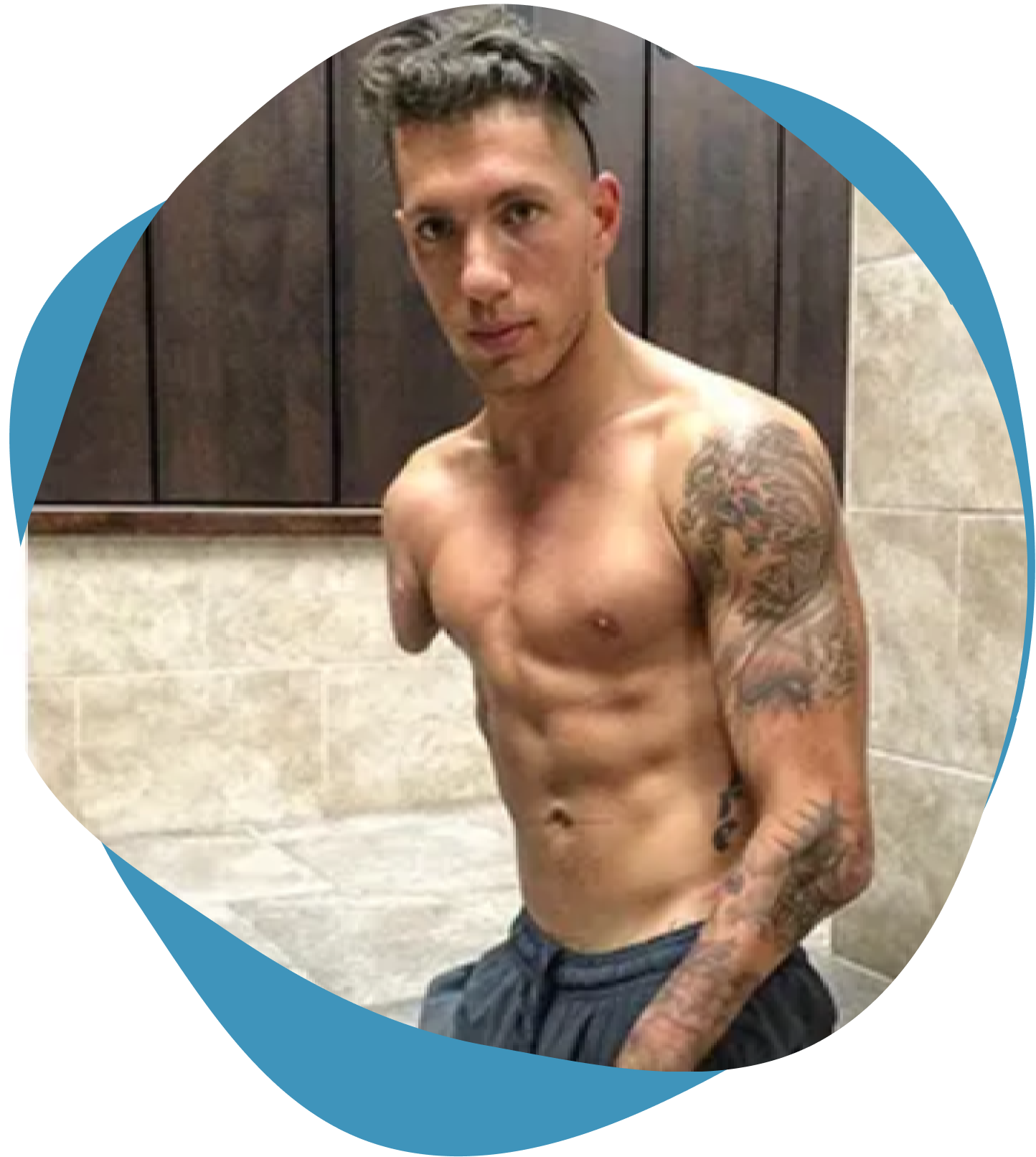 Fit man showing off tattoos and muscles indoors.