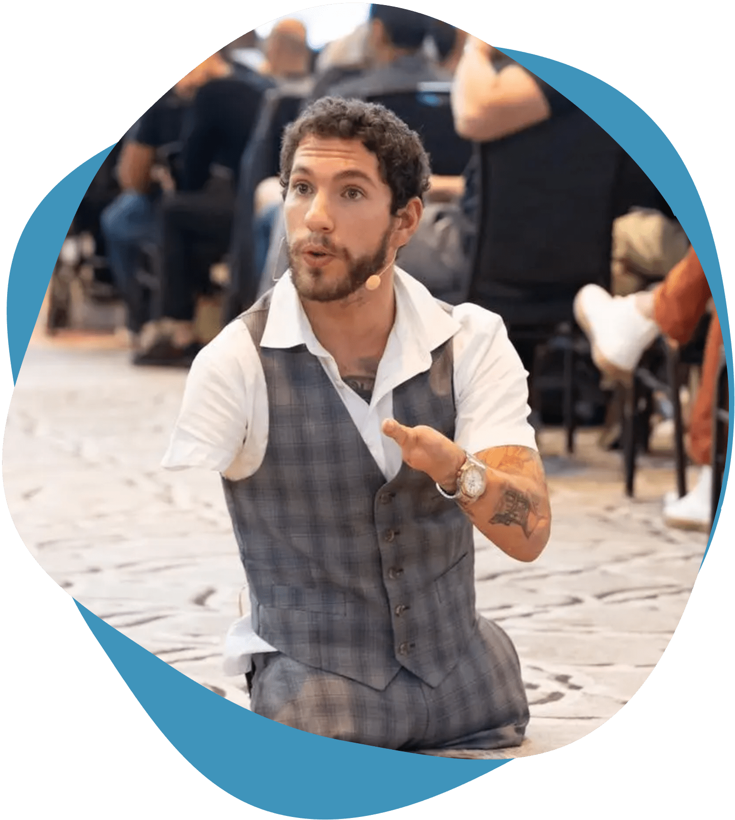 Man in a vest gesturing while speaking outdoors.