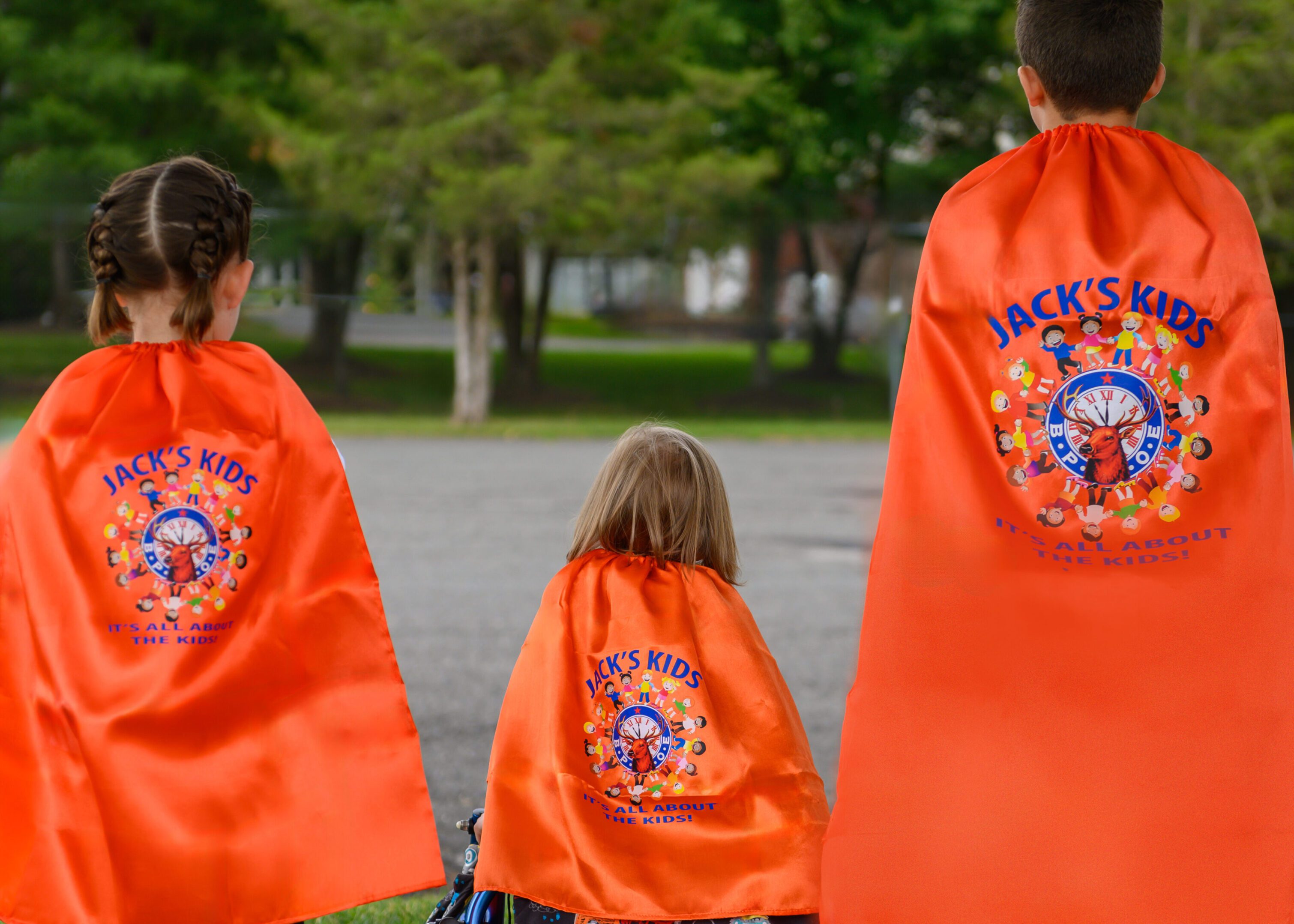 Jacks Kids Brochure Images Three children wearing bright orange capes outdoors.